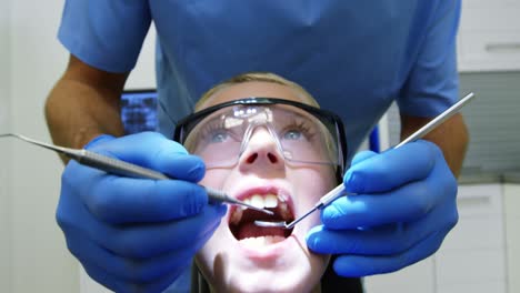 Dentist-examining-a-young-patient-with-tool