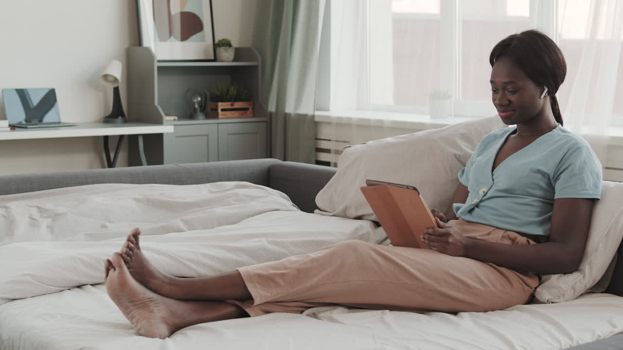 Young African-American Woman Using Tablet in Bed