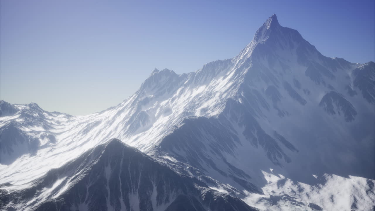 Snow blankets the steep slopes of a towering mountain reflecting sunlight