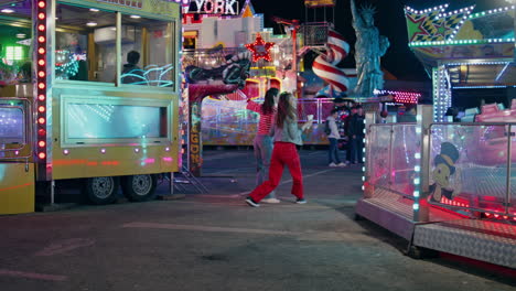 teenage girls walking amusement park rear view. happy best friends having fun