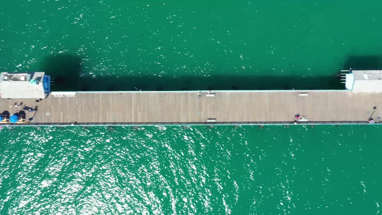 vista aérea de arriba hacia abajo de 4k sobre el muelle de san clemente, de un extremo a otro, con agua esmeralda y personas caminando por el muelle
