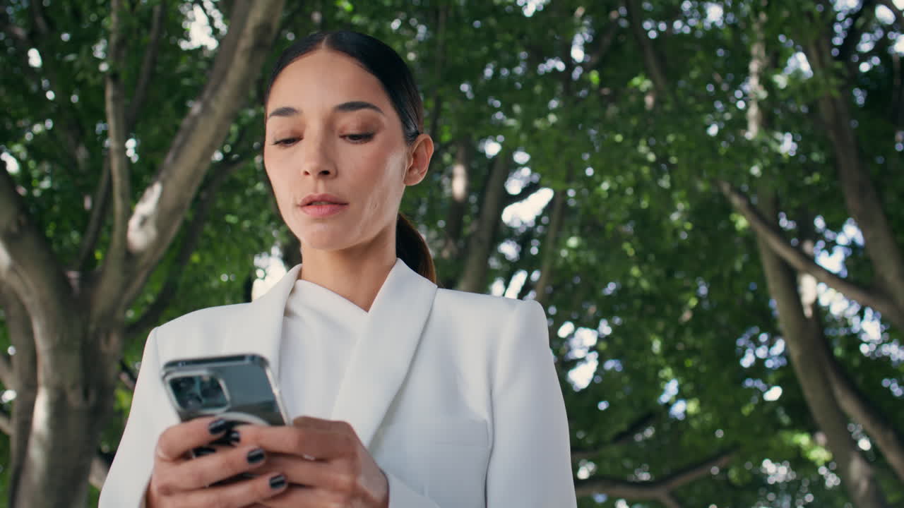 Beautiful lady looking smartphone walking garden close up. Woman scrolling phone