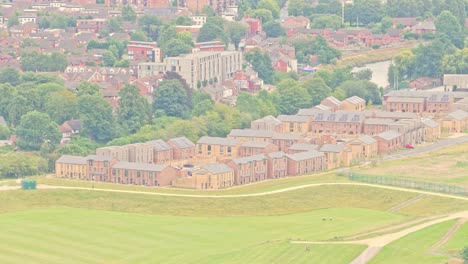 rows of contemporary brick townhouses and apartments stand near the river irwell alongside open green space in salford, england, captured in static aerial shot