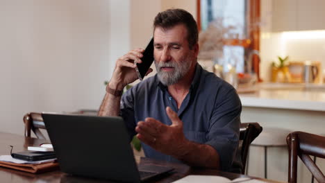 hombre trabajando desde casa en portátil y teléfono