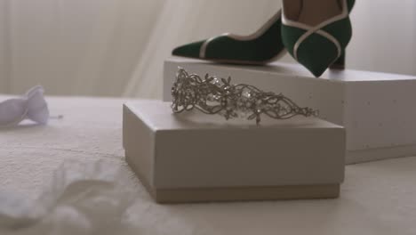 fotografía de cerca de tacones altos y tiara exhibidos antes de la ceremonia de la boda