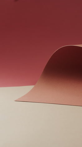 vertical video of close up of orange and red rolled paper on beige background with copy space