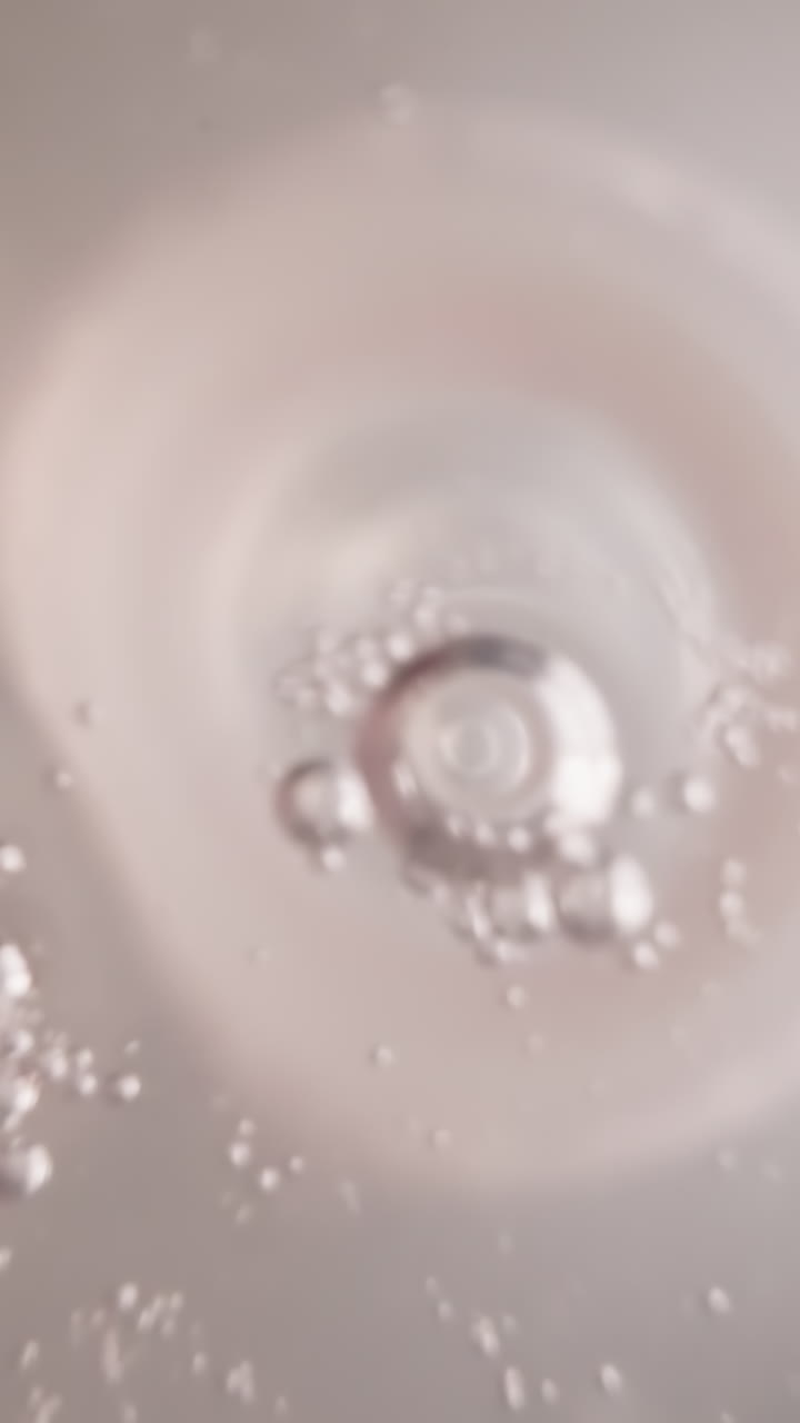 Clear water with oxygen bubbles oscillates in plastic bottle with white nipple. Refreshing drink in transparent container with measuring divisions macro