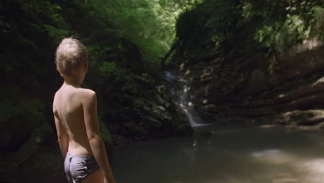 boy looking at a waterfall in a forest