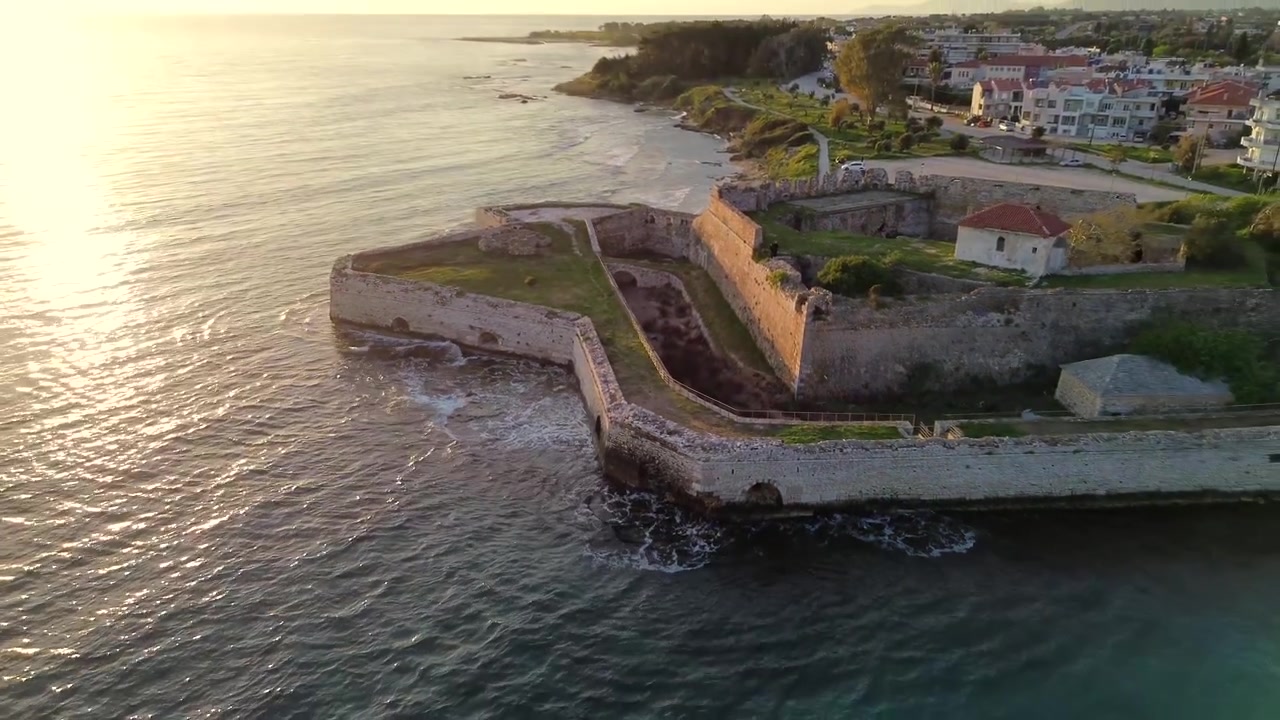 Ripresa con drone che si allontana, rivelando la storica fortezza in pietra del Castello di Pantokrator a Preveza, Grecia, durante un bellissimo tramonto sul Mar Ionio. Filmato 4K di alta qualità