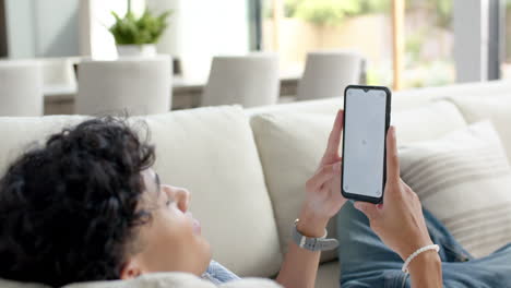 lying on couch, teenage boy using smartphone and relaxing at home