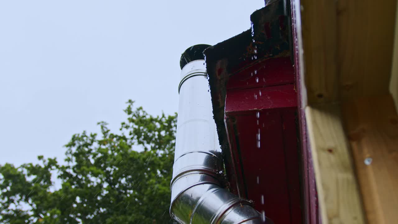 Rainy Serenity: Captured from inside a cozy home, this image showcases a clear raindrop hanging from a village rooftop