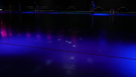 blue and red lights flashing on roller skating rink with people skating by in background party scene venue - in cinema 4k (30fps slowed from 60fps).