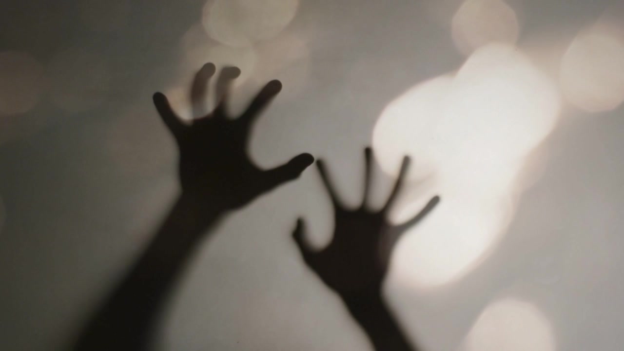 Mani in ombra, con il braccio superiore che si avvicina da sinistra, si alza, si allarga e si estende verso un bokeh luminoso.