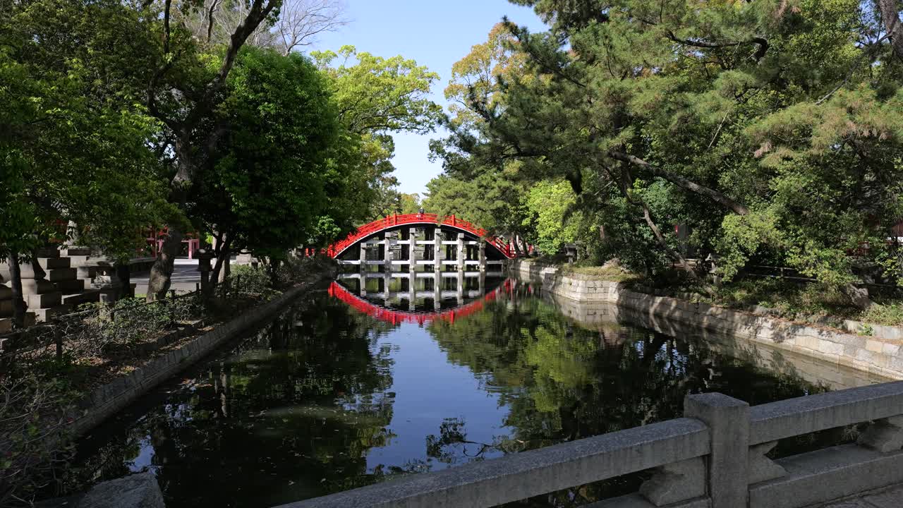 Vista panoramica del famoso ponte rosso ad arco Sorihashi (Drum Bridge) che si riflette nelle acque calme dello stagno presso il santuario Sumiyoshi Taisha a Osaka, Giappone, Asia