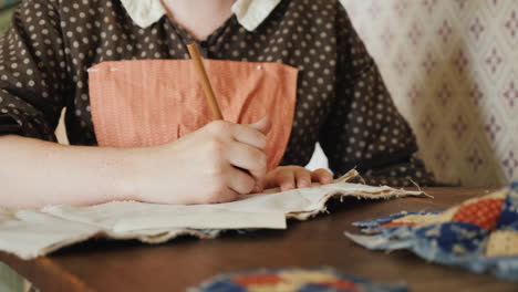 a woman in an antique dress from the time of the development of america is engaged in needlework