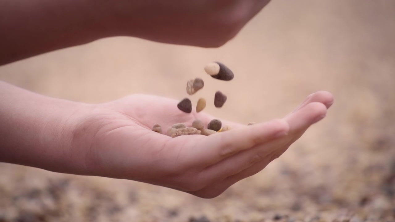 Småsten, der falder fra hånden i slowmotion