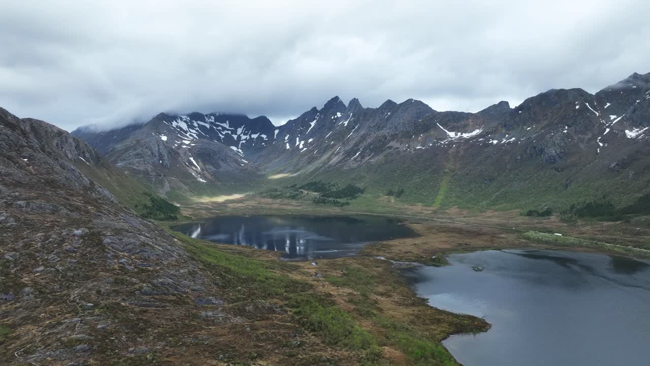 Drone reveals Hopsvatnet, Hopspollen and E10 road south of Svolvaer with rugged Lofoten peaks in spring