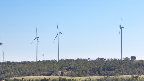 Telephoto-Drone-View-Of-Tall-Wind-Turbines-Spinning-On-Countryside-Hill,-4K