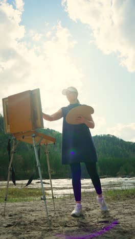 woman painting outdoors by a river