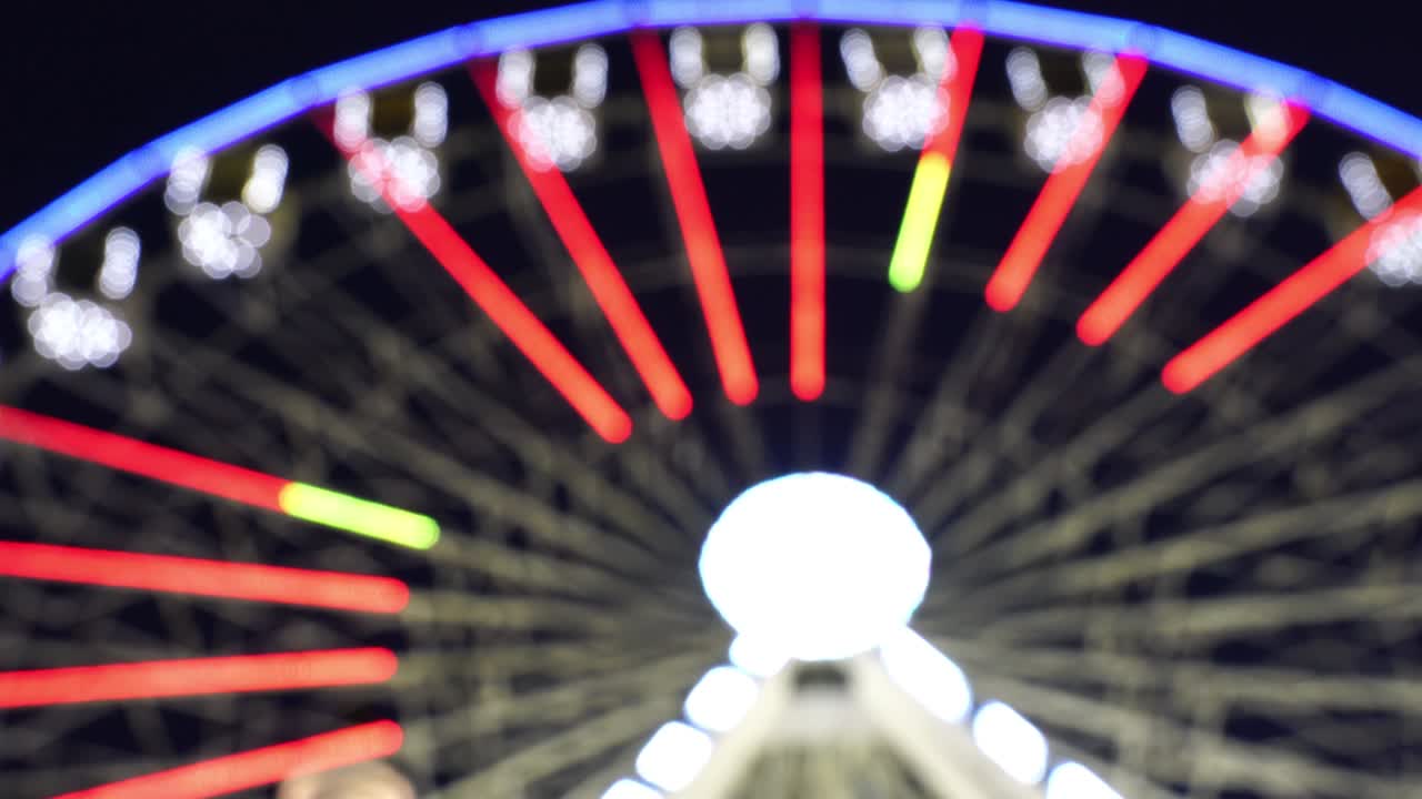 밤하늘 배경에서 회전하는 밝은 페리스 은 초점을 벗어난 효과를 가지고 있습니다.