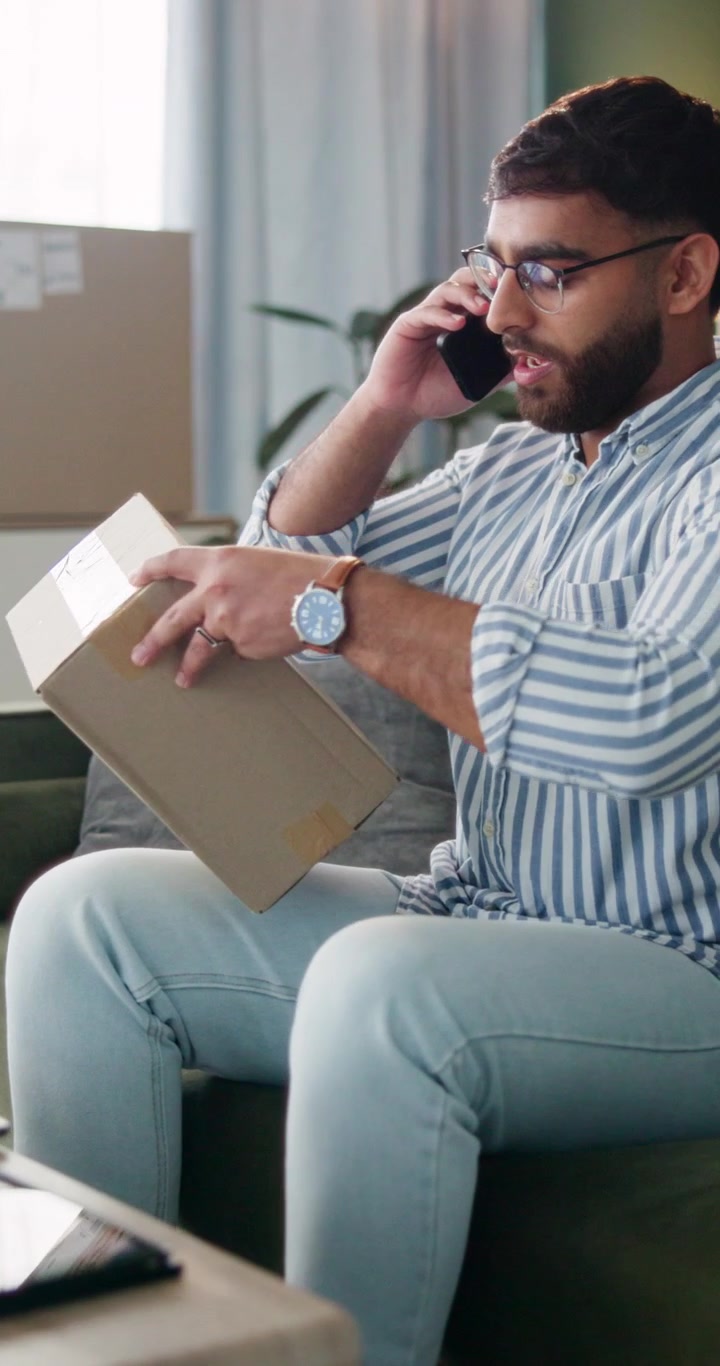 Man Talking on Phone While Inspecting a Package at Home