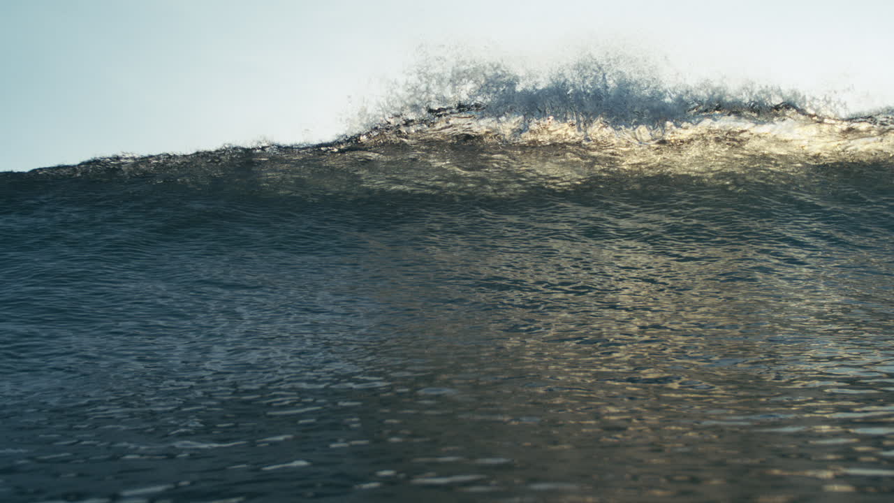 Cresting dark wave viewed from sea level in soft backlight with no people