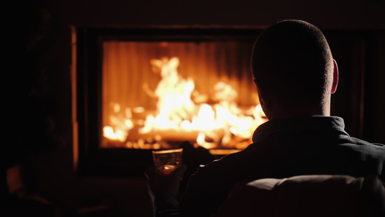 알코올 겨울 에스 한 잔과 함께 벽난로 옆에 앉아 자신감 있는 중년 남자의 실루엣