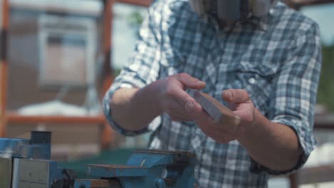 carpenter removing teak wood trim from vice and sighting down line checking accuracy