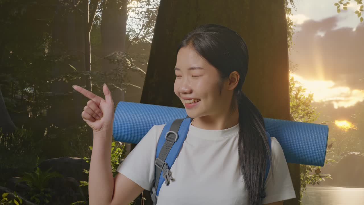 близкий взгляд на азиатскую туристку с альпинистским рюкзаком, улыбающаяся и указывающая в сторону во время исследования лесной природы