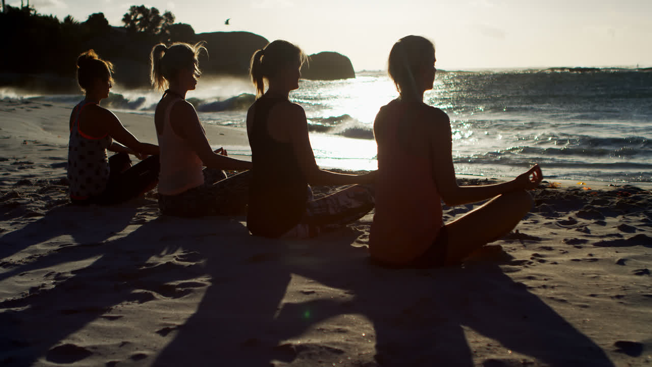 여자 배구 선수들이 해변에서 요가를 수행합니다.