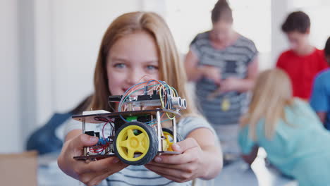 Portrait Of Female Student Holding Robot Vehicle In After School Computer Coding Class