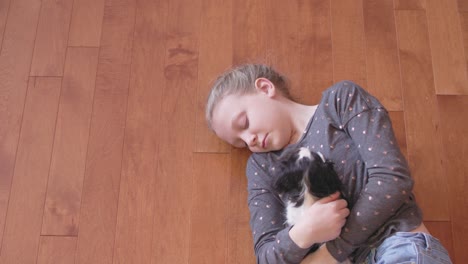 little girl hugging, and petting her adorable puppy on a wooden floor