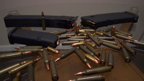 slider shot showing hoard of ar-15 ammo and gun magazines laying on a glass table