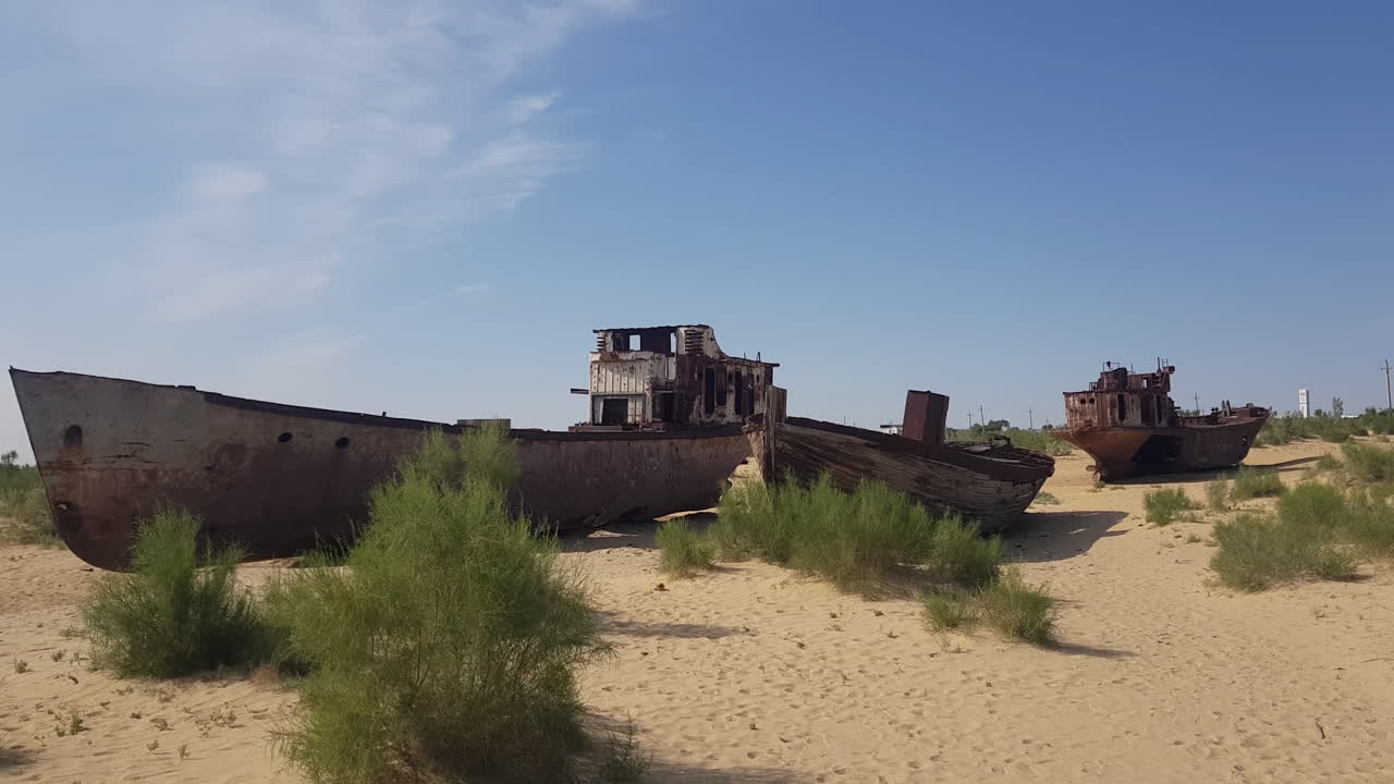 Navi e imbarcazioni arrugginite e abbandonate in decomposizione nella sabbia dell'ex Mar d'Aral, Asia Centrale, scenario apocalittico, panorama.