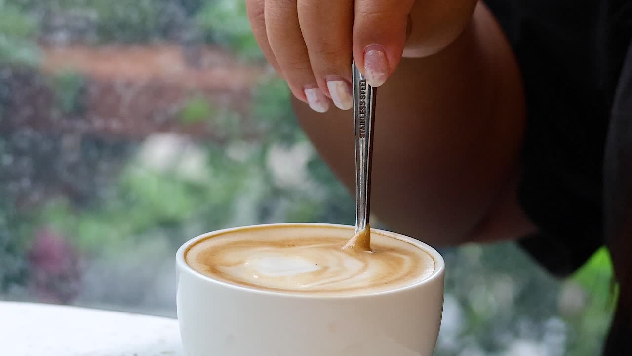Hand stirring coffee in a cup