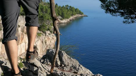 Viajero-Conquistando-Una-Montaña,-Excursionista-En-El-Borde-De-La-Cima-De-La-Montaña-Con-Vistas-Al-Mar