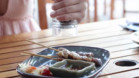 person seasoning food with a salt shaker