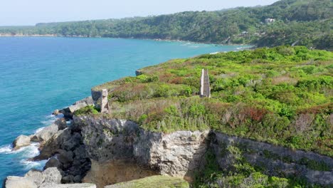 Epischer-Drohnenüberflug-über-Heruntergekommene-Leuchtturmruinen,-Die-Auf-Einer-Grasbedeckten-Klippe-Mit-Blick-Auf-Den-Atlantik-In-Cabo-France,-Dominikanische-Republik,-Sitzen