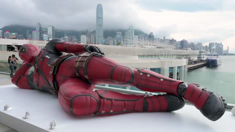 the 8-meter deadpool installation in hong kong, promoting disney’s "deadpool and wolverine" movie, attracts locals and tourists with the city skyline as a striking backdrop.