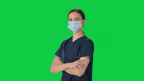 Indian-female-doctor-standing-crossed-hands-with-mask-on-Green-screen