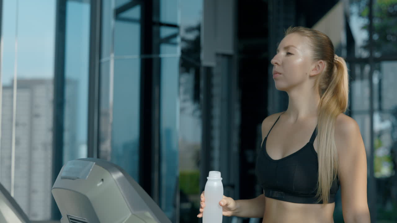 Woman on a Treadmill Drinking Water at the Gym