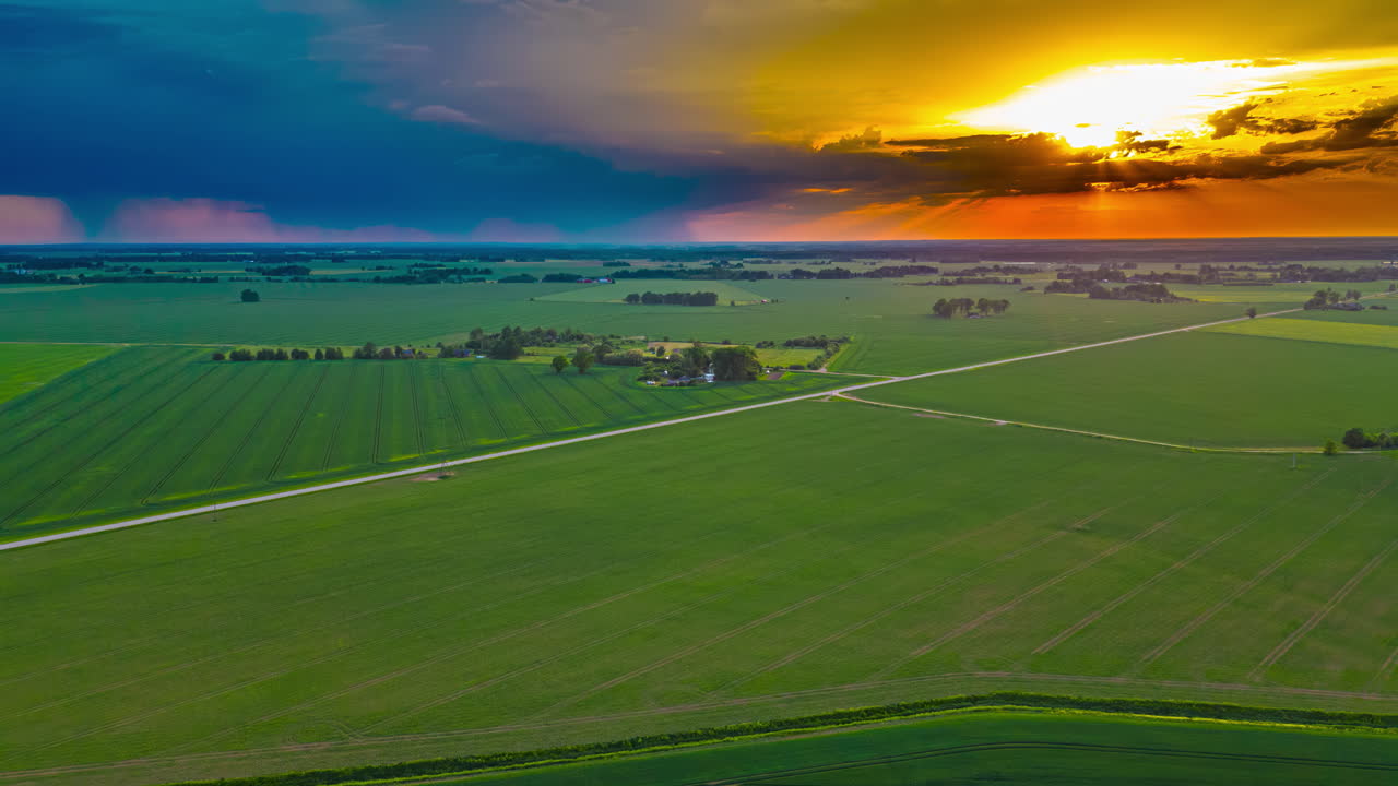 Tramonto colorato e una tempesta distante su campi coltivati - hyperlapse aereo.
