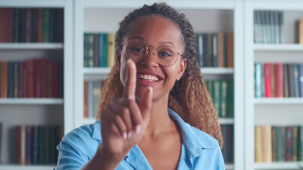 Young flirty african american woman points finger at screen and smiles nicely