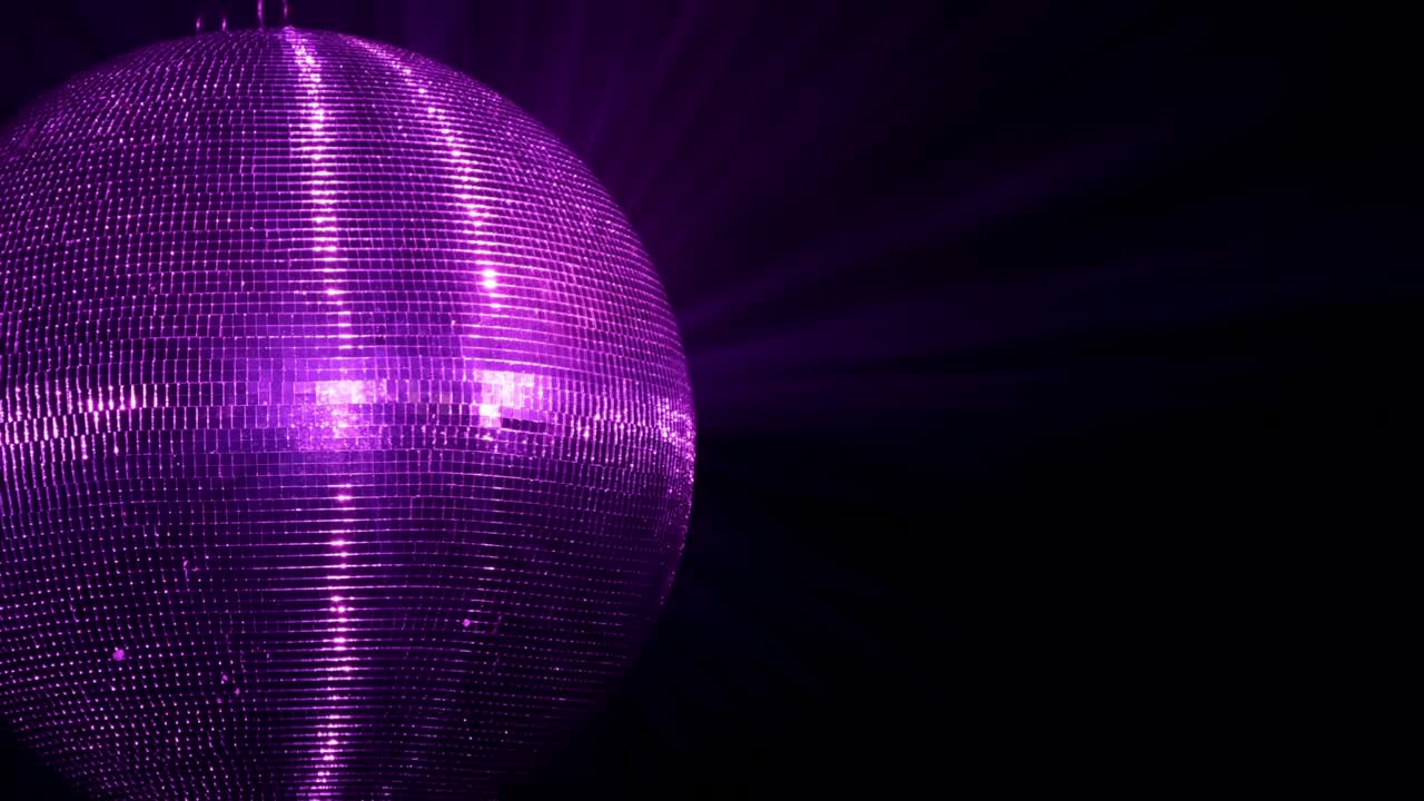 una pelota de discoteca espejada está girando en una fiesta. rayos rojos y azules de luz se reflejan de ella en el humo.