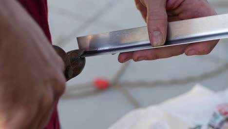 close up of the hands of a construction worker using tin snips while cutting a piece of aluminum angle iron sheet metal while building a teardrop travel trailer