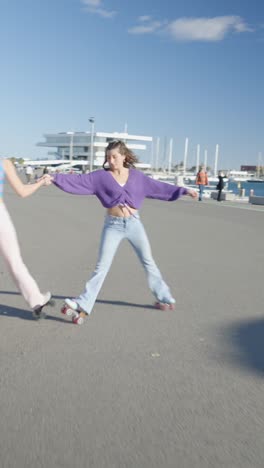two young women roller skating and having fun outdoors by the water