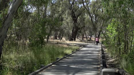 Beautiful-blonde-woman-walking-towards-camera-in-nature-on-bridge-footpath