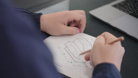 Primer-Plano-De-La-Mano-Del-Estudiante-Dibujando-El-Diseño-Del-Modelo-3d-En-Papel-Con-Lápiz,-4k