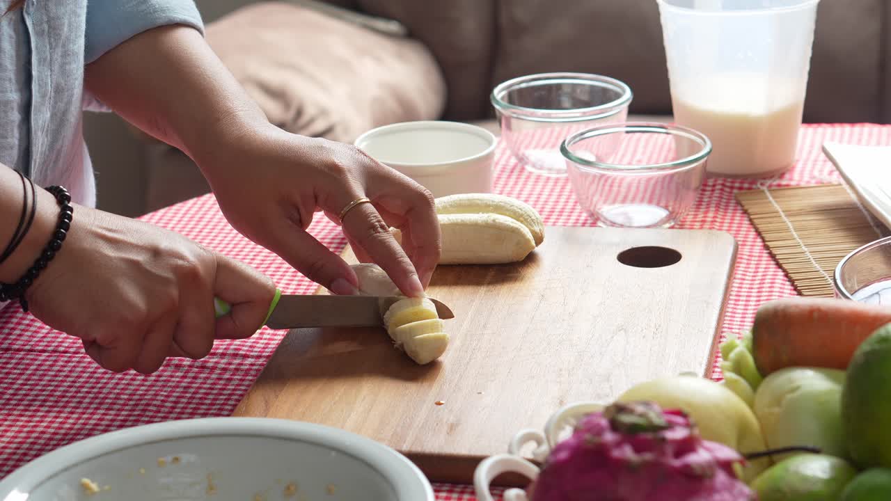 건강 한 신선 한 주스를 준비 하기 위해 칼로 바나나 를 잘라내는 젊은 여성 의 손