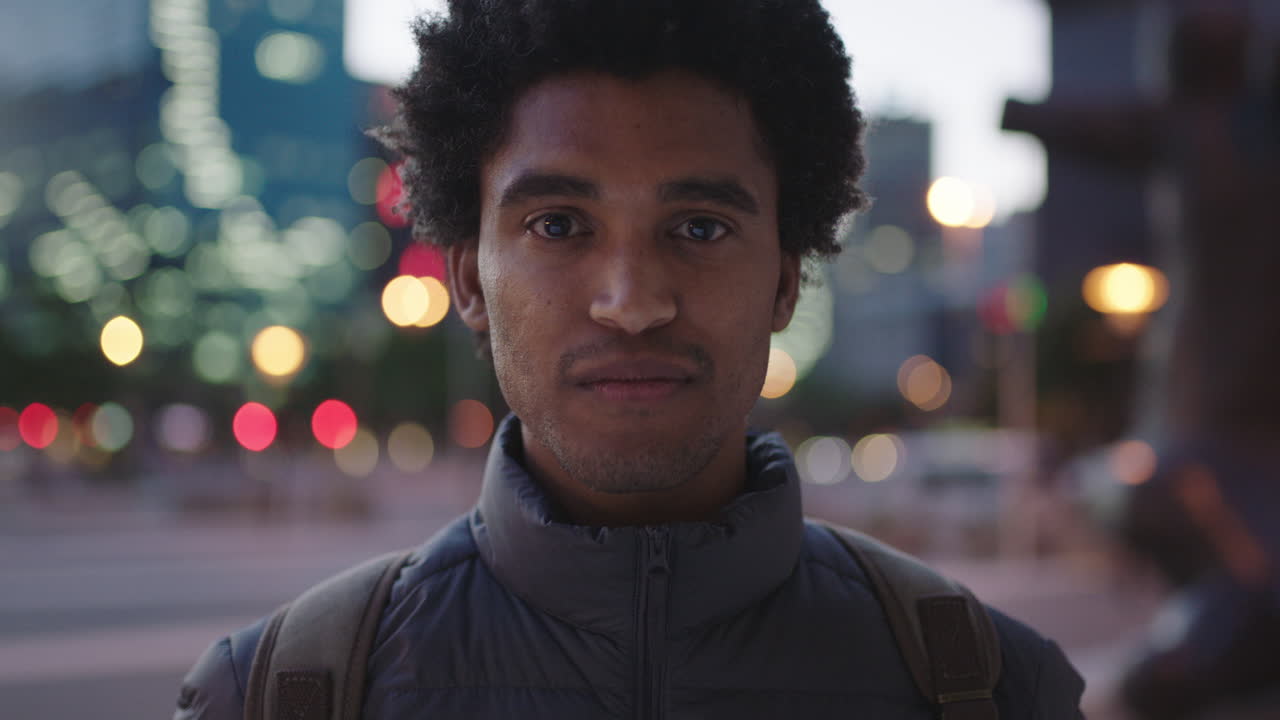 portrait of charming young mixed race man looking pensive at camera serious male in urban evening background